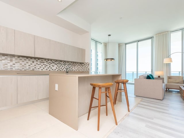 kitchen with decorative light fixtures, expansive windows, a breakfast bar area, and tasteful backsplash