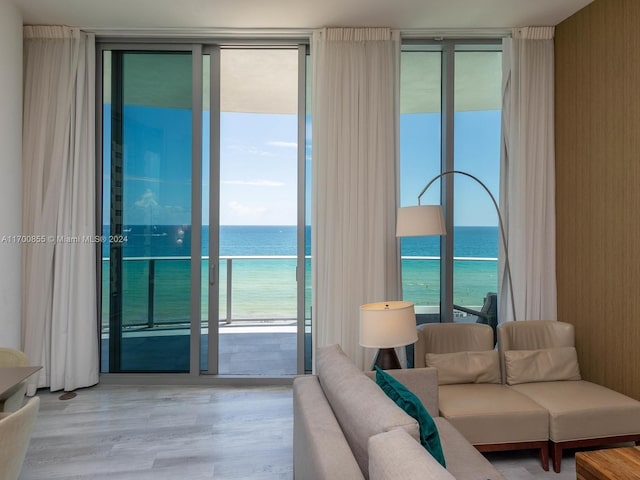 living room featuring wood-type flooring, a water view, plenty of natural light, and expansive windows