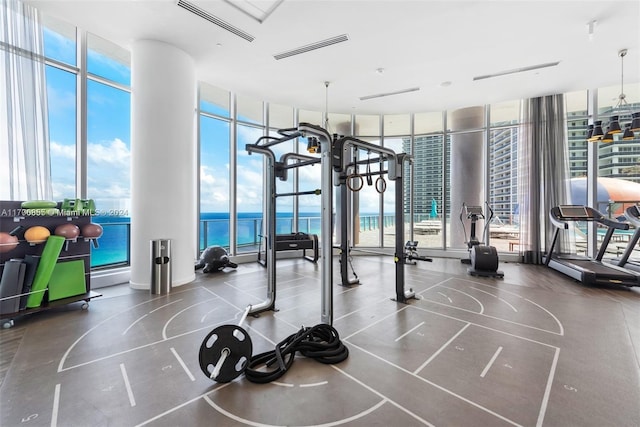 exercise room featuring a water view and floor to ceiling windows