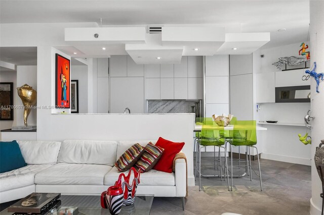 kitchen with white cabinetry, stainless steel oven, sink, a kitchen breakfast bar, and white fridge