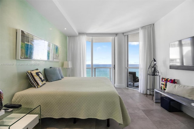 bedroom with expansive windows, a water view, and multiple windows