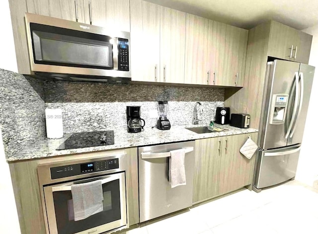 kitchen with light tile patterned flooring, stainless steel appliances, light stone counters, and sink