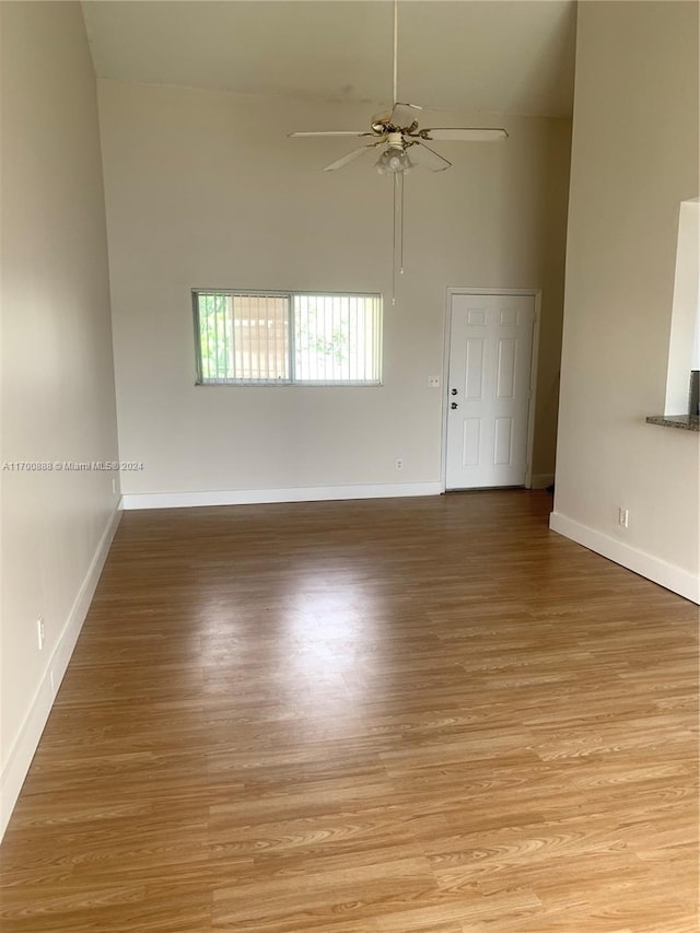 unfurnished room featuring ceiling fan, light hardwood / wood-style flooring, and a high ceiling