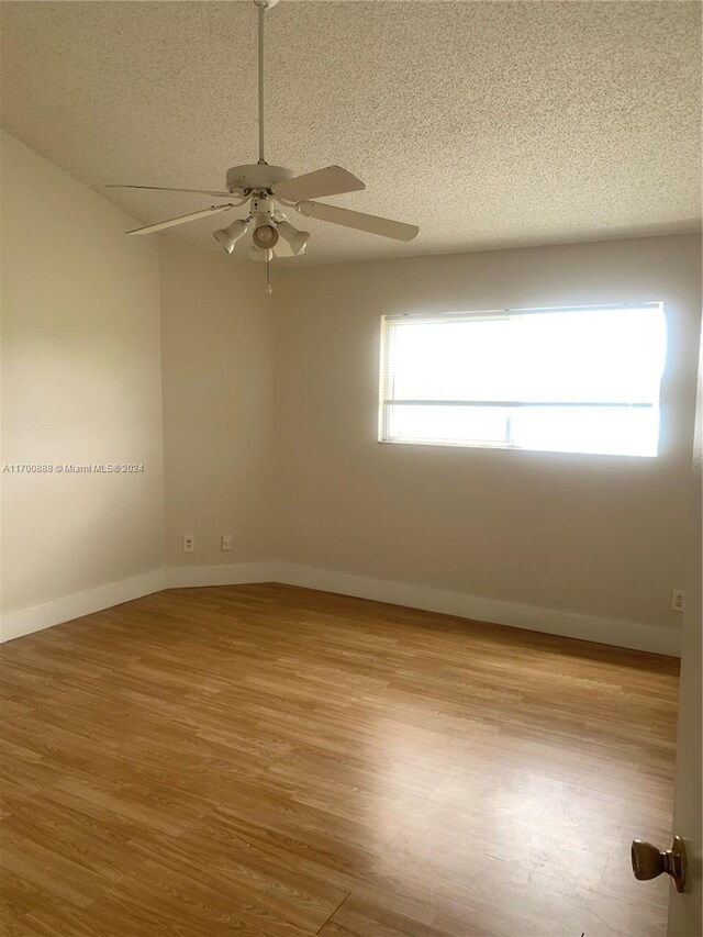 unfurnished room with a textured ceiling, light hardwood / wood-style floors, ceiling fan, and a healthy amount of sunlight