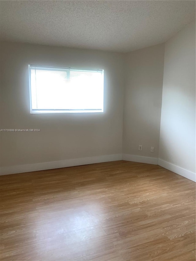 empty room featuring light hardwood / wood-style floors and a textured ceiling