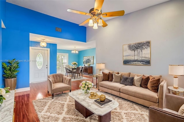 living room with wood-type flooring and ceiling fan with notable chandelier