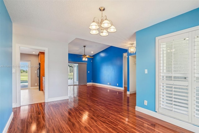 unfurnished living room with a wealth of natural light, wood-type flooring, and ceiling fan with notable chandelier