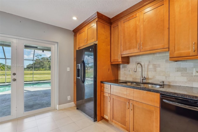 kitchen featuring dark stone counters, black appliances, sink, decorative backsplash, and a textured ceiling