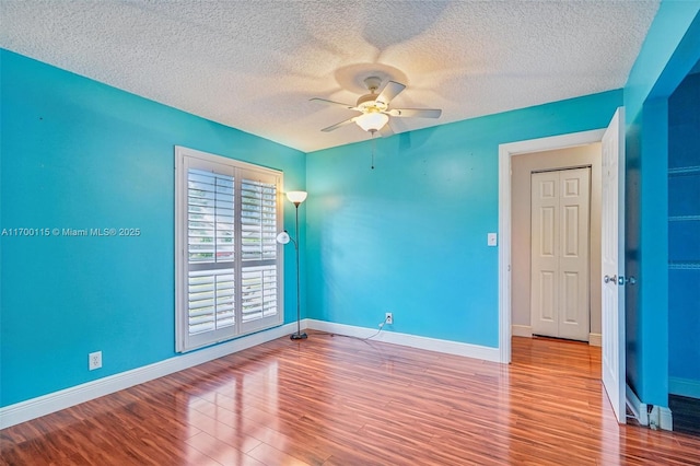 spare room with ceiling fan, light hardwood / wood-style floors, and a textured ceiling