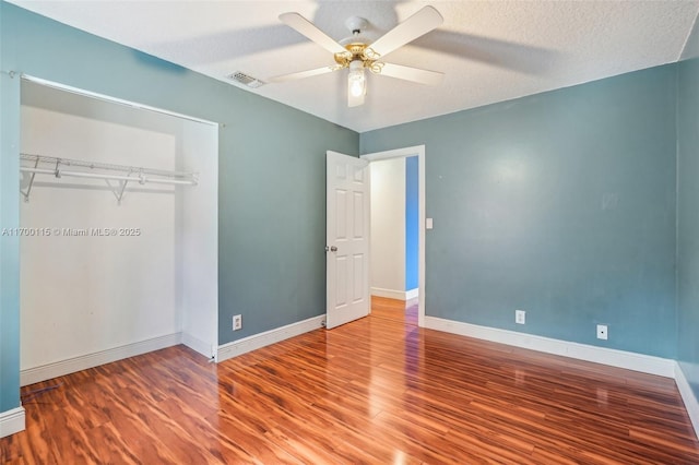 unfurnished bedroom featuring hardwood / wood-style floors, a textured ceiling, a closet, and ceiling fan