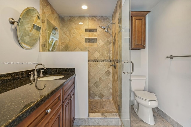 bathroom featuring tile patterned flooring, a shower with door, vanity, and toilet