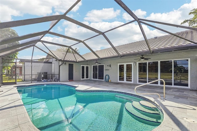 view of swimming pool with glass enclosure, ceiling fan, french doors, and a patio