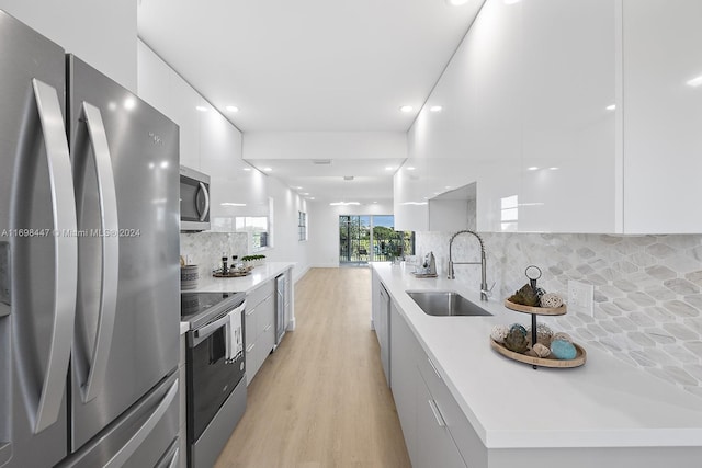 kitchen with backsplash, stainless steel appliances, white cabinetry, and sink