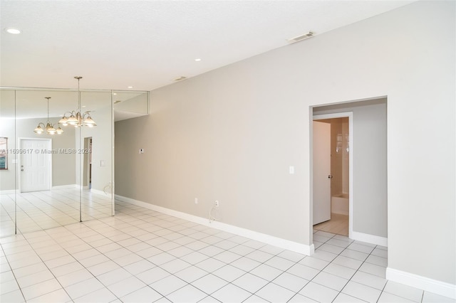 spare room with light tile patterned flooring and an inviting chandelier