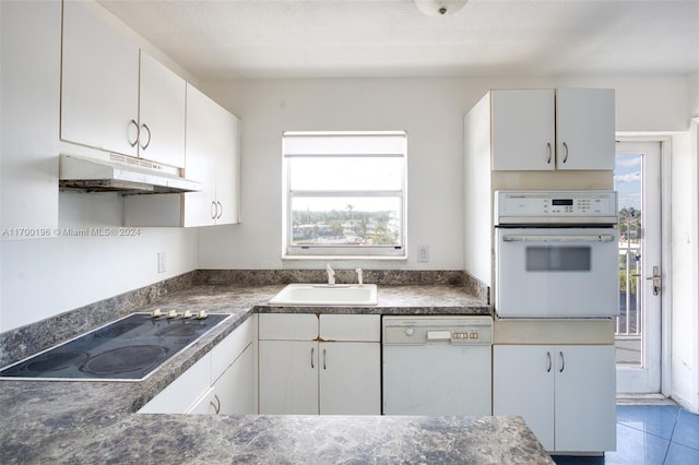 kitchen with white appliances, tile patterned floors, sink, a textured ceiling, and white cabinetry