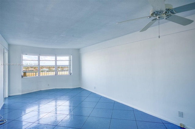 empty room featuring a textured ceiling, tile patterned floors, and ceiling fan