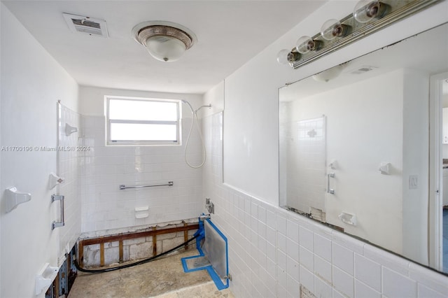 bathroom with tiled shower and tile walls