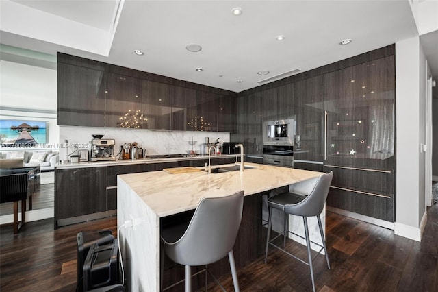 kitchen featuring dark hardwood / wood-style flooring, sink, a breakfast bar, and a center island with sink