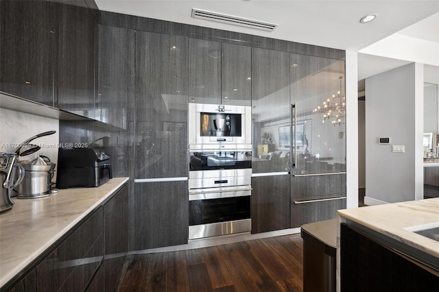 kitchen featuring decorative backsplash, dark wood-type flooring, and stainless steel double oven