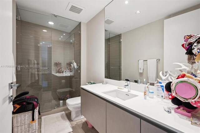 bathroom with vanity, toilet, and a shower with shower door