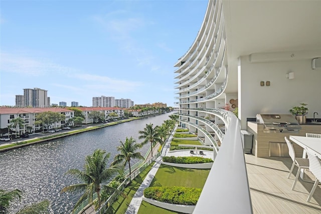 balcony with exterior kitchen, a water view, area for grilling, and sink