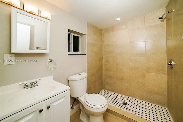 bathroom with tile patterned flooring, vanity, toilet, and tiled shower