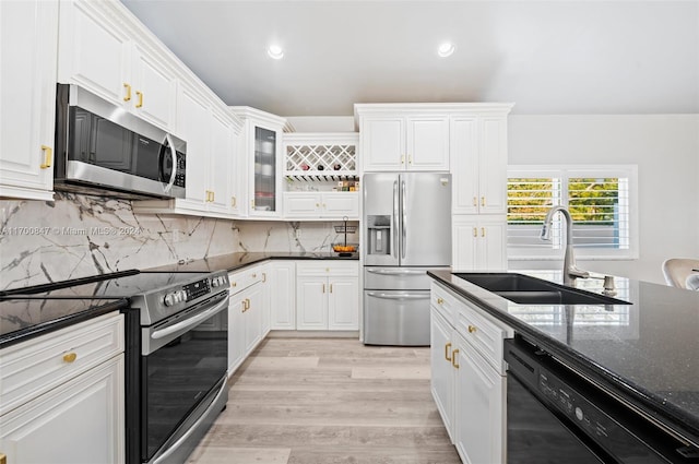 kitchen with dark stone counters, sink, white cabinets, and stainless steel appliances