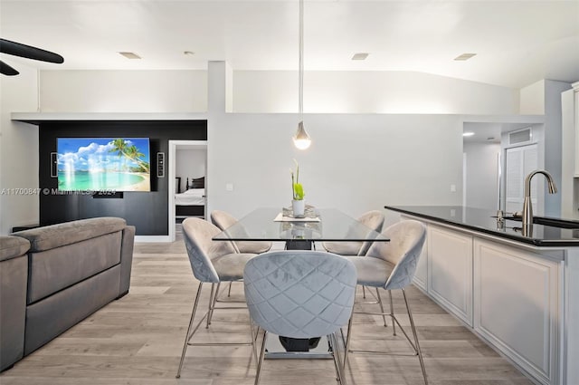 dining room with light hardwood / wood-style floors, vaulted ceiling, ceiling fan, and sink