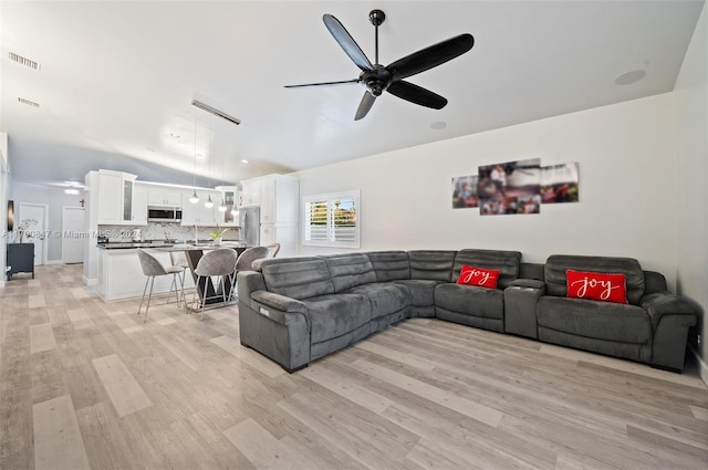 living room with light hardwood / wood-style flooring and ceiling fan