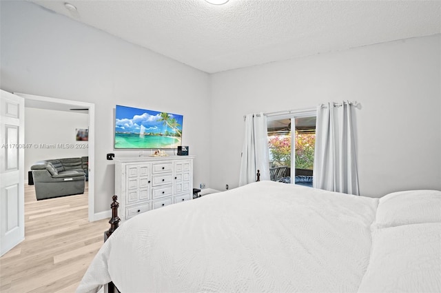 bedroom with access to exterior, a textured ceiling, and light wood-type flooring