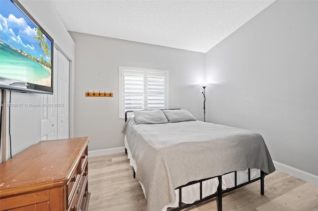 bedroom with a textured ceiling and light wood-type flooring