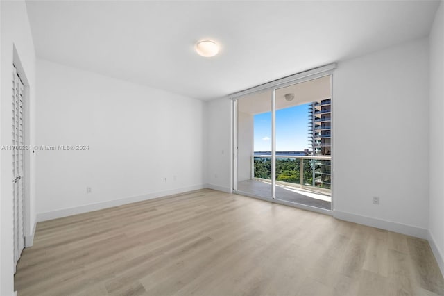 empty room featuring a wall of windows and light wood-type flooring