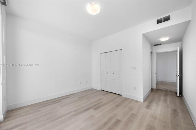 unfurnished bedroom featuring light wood-type flooring and a closet