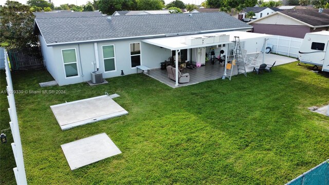 back of property with a lawn, a patio area, a pergola, and central AC