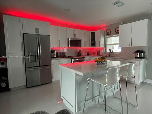 kitchen featuring a center island, a kitchen breakfast bar, sink, decorative backsplash, and appliances with stainless steel finishes