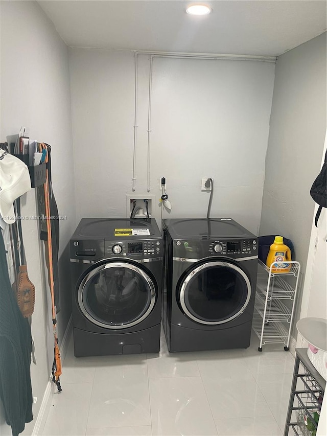 clothes washing area featuring washer and dryer and light tile patterned flooring