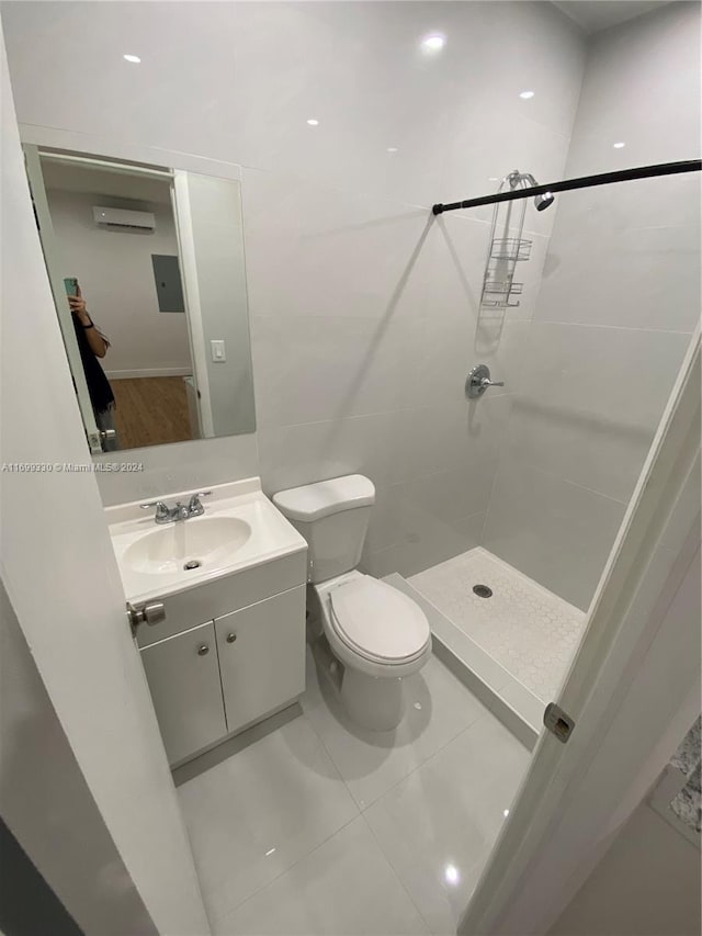 bathroom with a wall mounted air conditioner, vanity, a shower, tile patterned flooring, and toilet