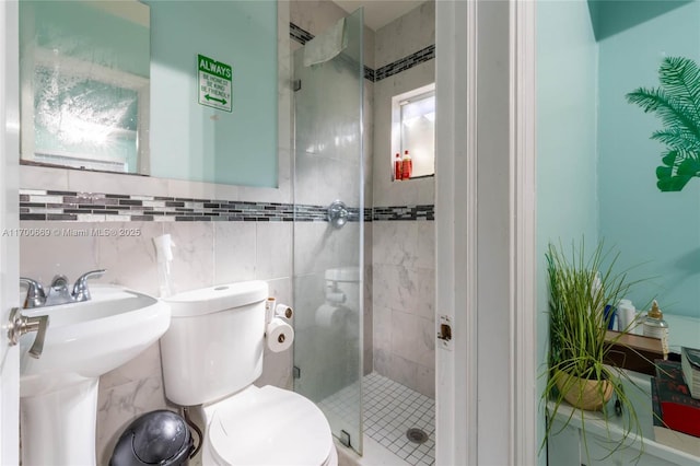 bathroom featuring tile walls, an enclosed shower, sink, and toilet