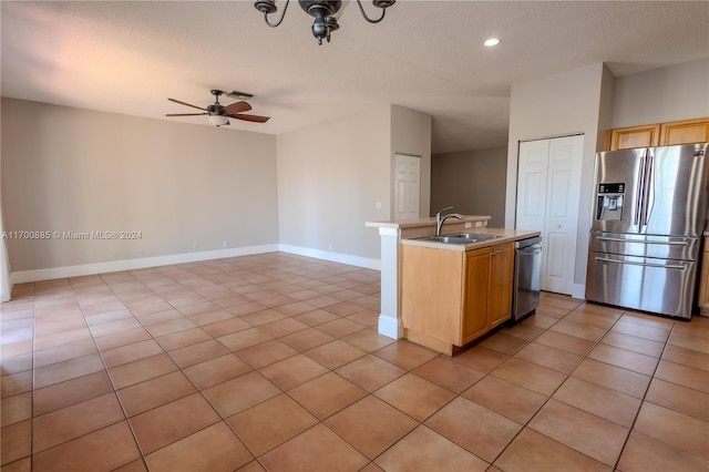 kitchen with appliances with stainless steel finishes, ceiling fan, a kitchen island with sink, sink, and light brown cabinets