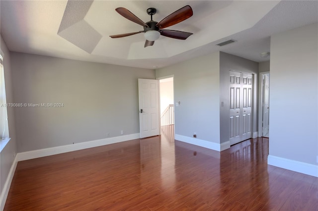 unfurnished room featuring ceiling fan, dark hardwood / wood-style flooring, a textured ceiling, and a tray ceiling