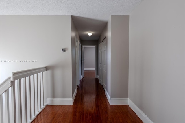 hall with a textured ceiling and dark wood-type flooring