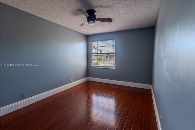 empty room with ceiling fan, dark wood-type flooring, and a textured ceiling