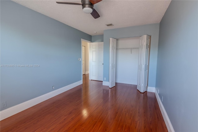 unfurnished bedroom with a textured ceiling, ceiling fan, a closet, and dark hardwood / wood-style floors