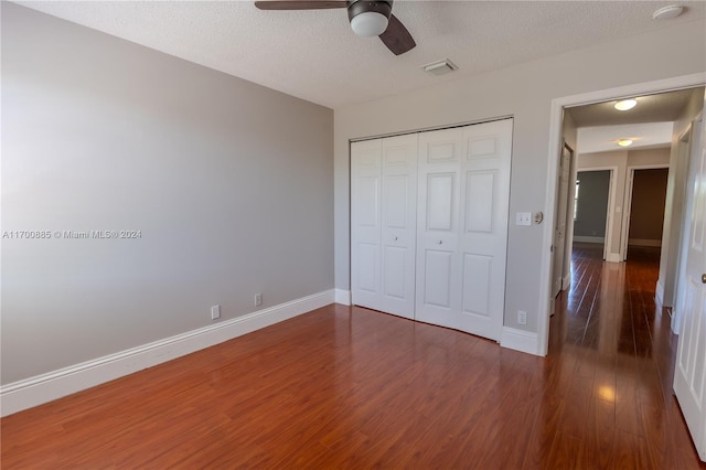 unfurnished bedroom with a textured ceiling, a closet, dark hardwood / wood-style floors, and ceiling fan