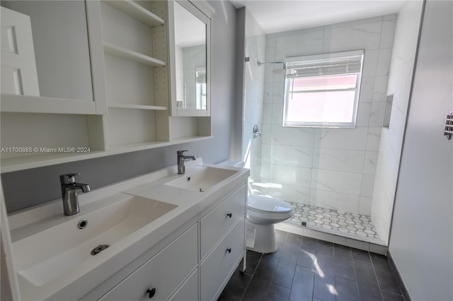 bathroom with tiled shower, vanity, and toilet