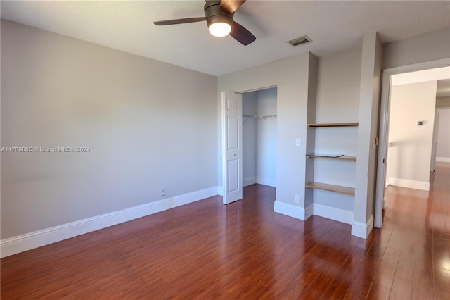 unfurnished bedroom with a textured ceiling, dark hardwood / wood-style flooring, a closet, and ceiling fan