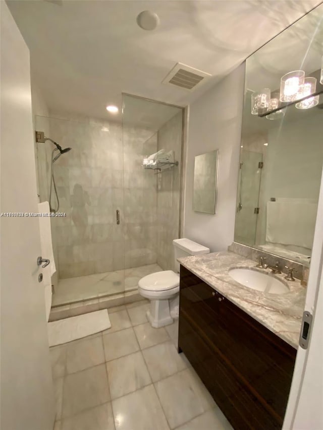 bathroom featuring tile patterned floors, vanity, toilet, and an enclosed shower