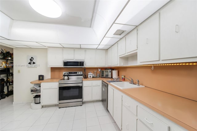 kitchen with visible vents, stainless steel appliances, light countertops, white cabinetry, and a sink