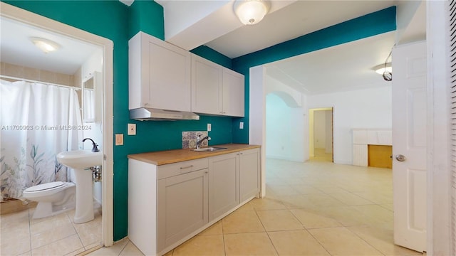 kitchen featuring light tile patterned flooring, white cabinetry, and sink