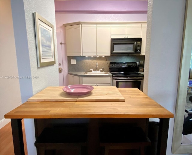 kitchen featuring decorative backsplash, sink, black appliances, and light hardwood / wood-style floors